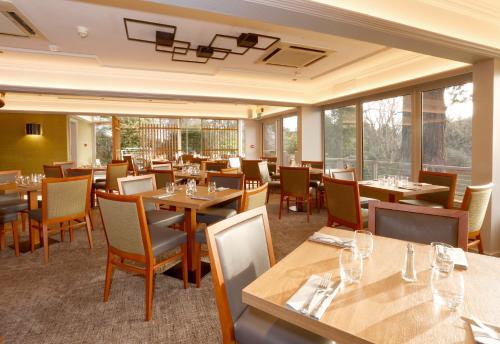 a restaurant with wooden tables and chairs and windows at Invercarse Hotel Dundee, BW Signature Collection in Dundee