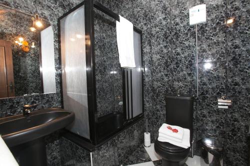 a black bathroom with a sink and a toilet at Agroturismo Izarre in Errezil