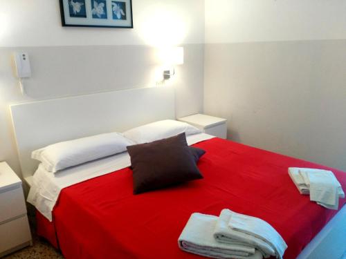 リミニにあるHotel Marittimoのベッドルーム1室(赤いベッド1台、タオル付)