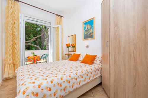 um quarto com uma cama com almofadas laranja e uma janela em Apartment Ivo & Mare em Dubrovnik