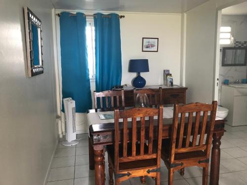 a dining room with a table and chairs and blue curtains at Les Bungalows du Mont-Auban in Sainte-Clotilde