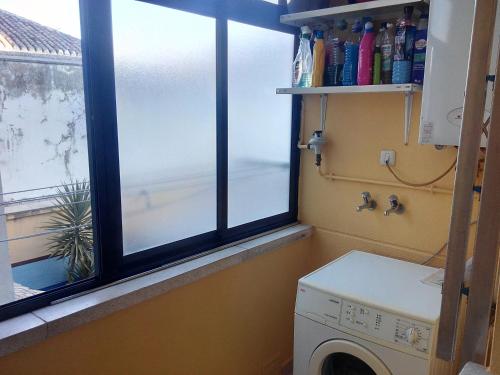a laundry room with two windows and a washing machine at Andrea´s place in Ciudad Real