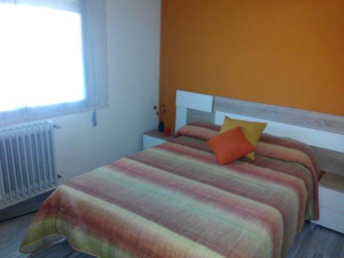 Schlafzimmer mit einem Bett mit orangefarbenem Kissen in der Unterkunft Andrea´s place in Ciudad Real