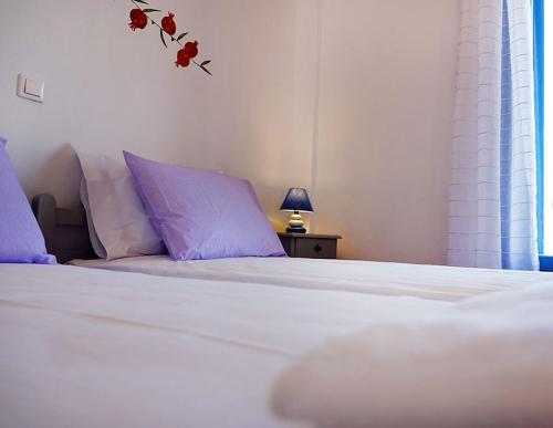 a bedroom with a white bed with purple pillows at Flora Apartments in Drios