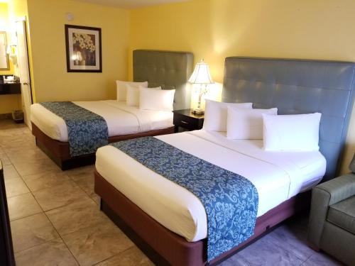 a hotel room with two beds and a couch at Shining Light Inn & Suites in Kissimmee