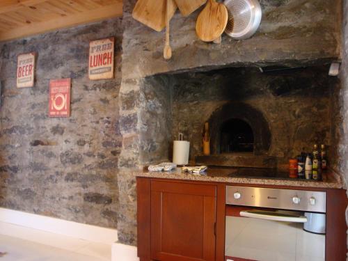 a kitchen with a stone wall with a stove at Vila Vinha in Arco da Calheta