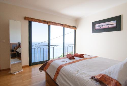 een slaapkamer met een bed en een groot raam bij Casa Nici in Calheta