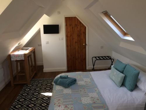 ein Schlafzimmer mit einem Bett im Dachgeschoss mit einem Fenster in der Unterkunft Pump View in Weymouth