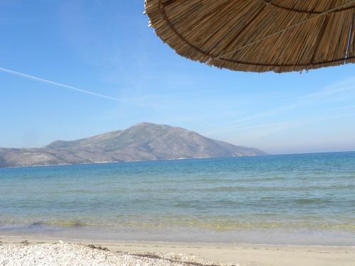 a beach with a straw umbrella and the ocean at Apartment Soleal Orikum in Orikum