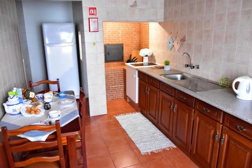 uma cozinha com uma mesa, um lavatório e um frigorífico em LAGOON'S HOUSE em Sete Cidades