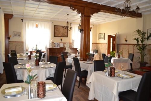 a dining room with white tables and black chairs at Logis Hôtel Restaurant La Tête Des Faux in Le Bonhomme