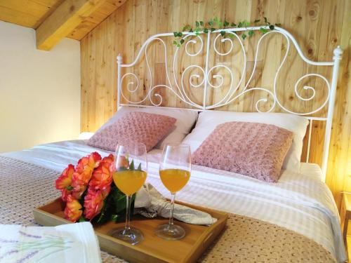 a bed with two glasses of wine and flowers on a tray at Apartment Cernesa in Ražanac