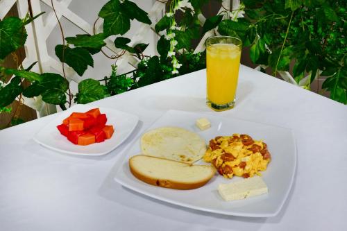 a white table with two plates of food and a glass of orange juice at Hotel Florida Sincelejo in Sincelejo