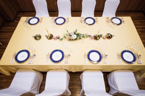 a table with white chairs and blue plates and flowers at Hotel Port Plaza Chiba in Chiba