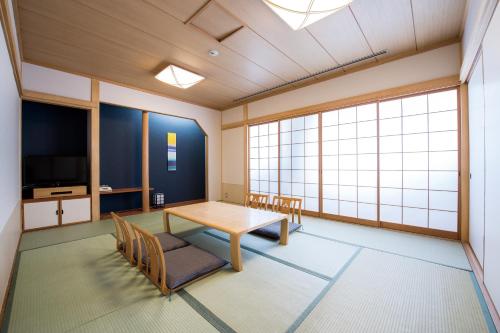 a room with a table and chairs and a television at Hotel Port Plaza Chiba in Chiba