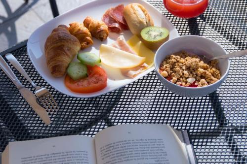 a plate of food on a table with a book at Hotel Rossovino Como in Como