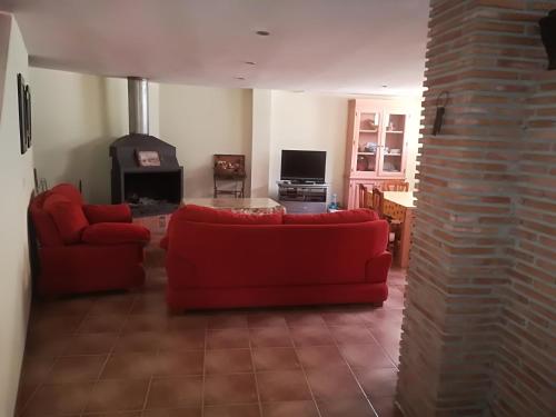 ein Wohnzimmer mit einem roten Sofa und einem Kamin in der Unterkunft PERGAR DESCANSO-15 minutos Playa-Motril Ferry in Acebuches