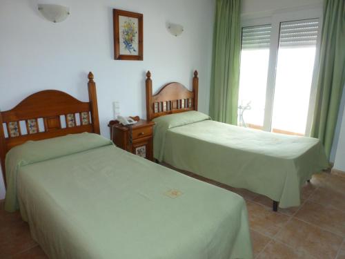 a bedroom with two beds and a window at Hostal Cortés in Garrucha