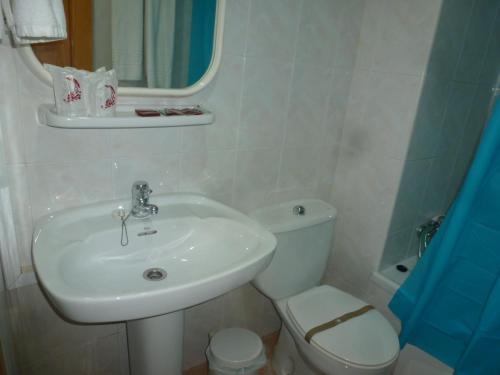 a bathroom with a sink and a toilet and a mirror at Hostal Cortés in Garrucha