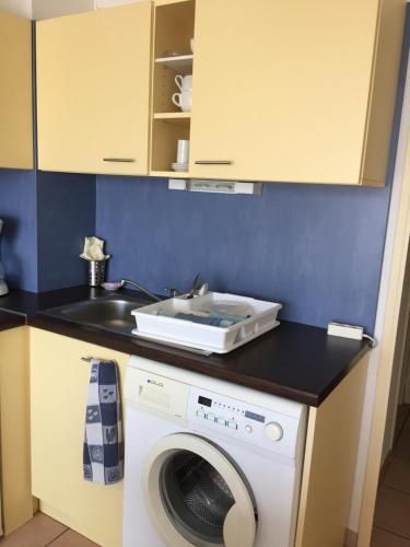uma cozinha com uma máquina de lavar roupa e um lavatório em Appartement dans Les jardins de Phoebus em Gruissan