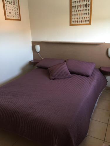 Appartement dans Les jardins de Phoebus في جرويسان: سرير مع أغطية ووسائد أرجوانية في الغرفة