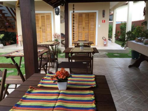 un patio con mesas, sillas y una alfombra en Pousada da Brisa, en Itanhaém