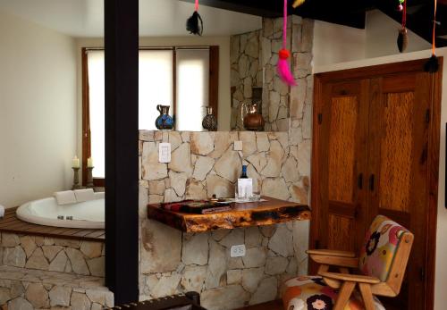 a bathroom with a stone wall and a bath tub at Kkala Boutique Hotel in Salta