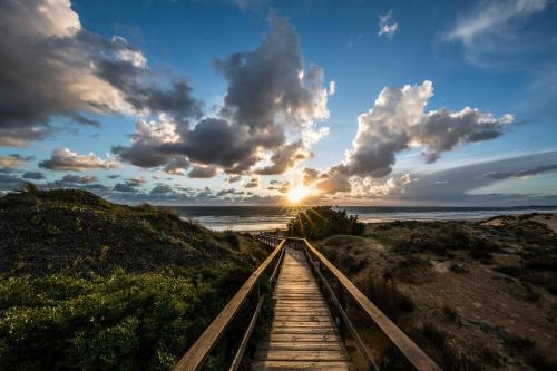 a wooden pathway leading to the beach with the sunset at Palacio de Sancti Petri, a Gran Meliá - The Leading Hotels of the World in Chiclana de la Frontera