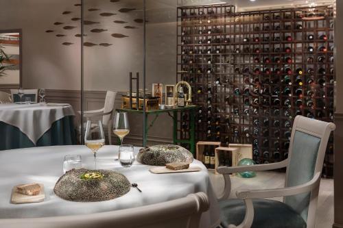 a table with glasses of wine and a wall of wine bottles at Palacio de Sancti Petri, a Gran Meliá - The Leading Hotels of the World in Chiclana de la Frontera