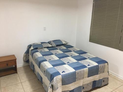 Una cama en un dormitorio con una manta azul y blanca en Confortável Residencia em Carlos Barbosa en Carlos Barbosa