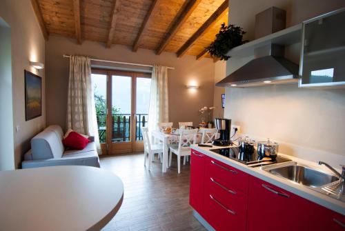 a kitchen with red cabinets and a dining room with a table at Agriturismo La Zangola in Tremosine Sul Garda
