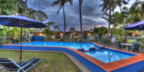 a swimming pool with two chairs and an umbrella at Sunlover Lodge in Kinka