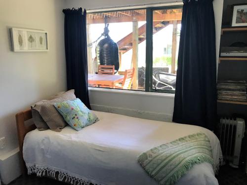 uma cama num quarto com uma grande janela em Tata Beach Apartment em Tarakohe