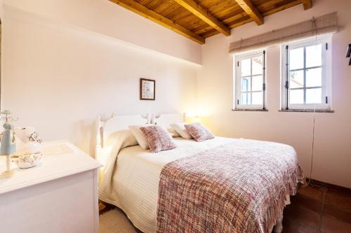 Una habitación blanca con una cama y una ventana en Monte do Medronhal, en Grândola