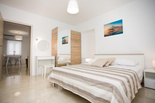 a white bedroom with a bed and a desk at Apartment Bilo in Omiš