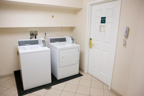 a laundry room with a washer and dryer next to a door at Host Inn an All Suites Hotel in Wilkes-Barre