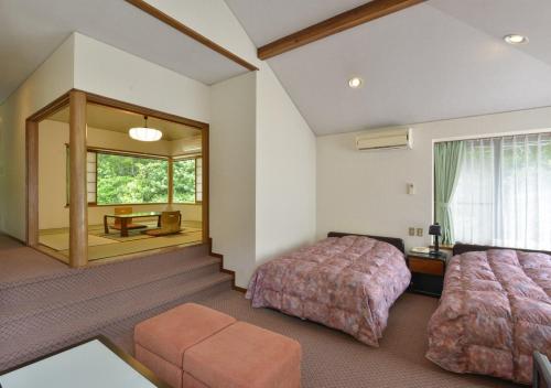 a bedroom with two beds and a large window at Le Nessa Akazawa in Ito