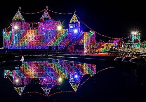 a house covered in christmas lights is reflected in the water at Le Nessa Akazawa in Ito