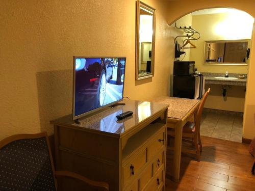 einen TV auf einer Kommode in einem Zimmer mit einem Tisch in der Unterkunft Sun Star Inn in Los Banos