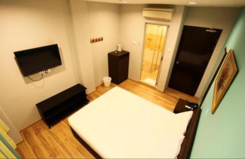Habitación pequeña con cama y TV de pantalla plana. en Hotel Conforto en Singapur