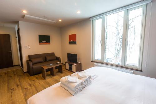 a bedroom with a bed and a couch and a window at SnowDog Village in Niseko