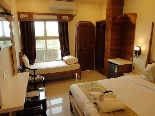 a bedroom with a bed and a window with a chair at Hotel Temple On Ganges in Varanasi