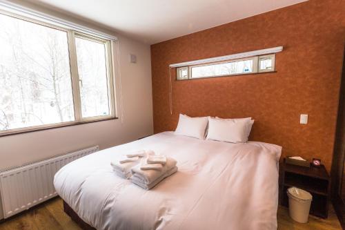 a bedroom with a bed with white towels on it at SnowDog Village in Niseko