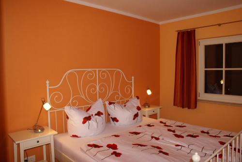 ヴストロにあるFerienhaus Fischlandperleのベッドルーム1室(赤い花の白いベッド1台付)