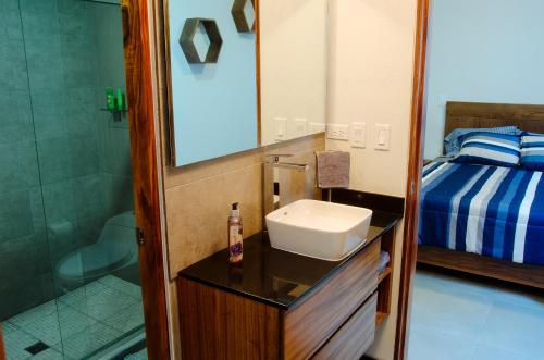 a bathroom with a sink and a bed and a mirror at El Refugio in Ensenada