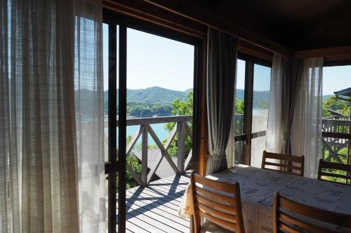 a dining room with a table and a balcony with windows at Kokuminshukusha Shodoshima in Shodoshima