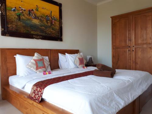 a bedroom with a large white bed with a painting on the wall at Amed Sunset Beach in Amed