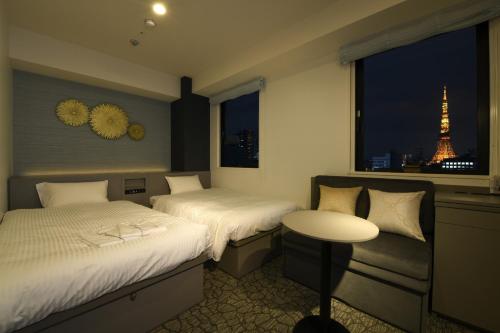 two beds in a room with a view of the eiffel tower at Henn na Hotel Tokyo Hamamatsucho in Tokyo