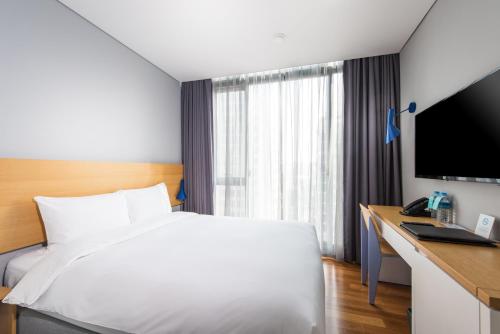 a hotel room with a bed and a desk and a television at Hotel Peyto Gangnam in Seoul