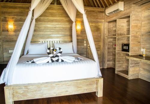 - une chambre avec un lit dans une pièce dotée de murs en bois dans l'établissement Ombak Bay Lembongan, à Nusa Lembongan